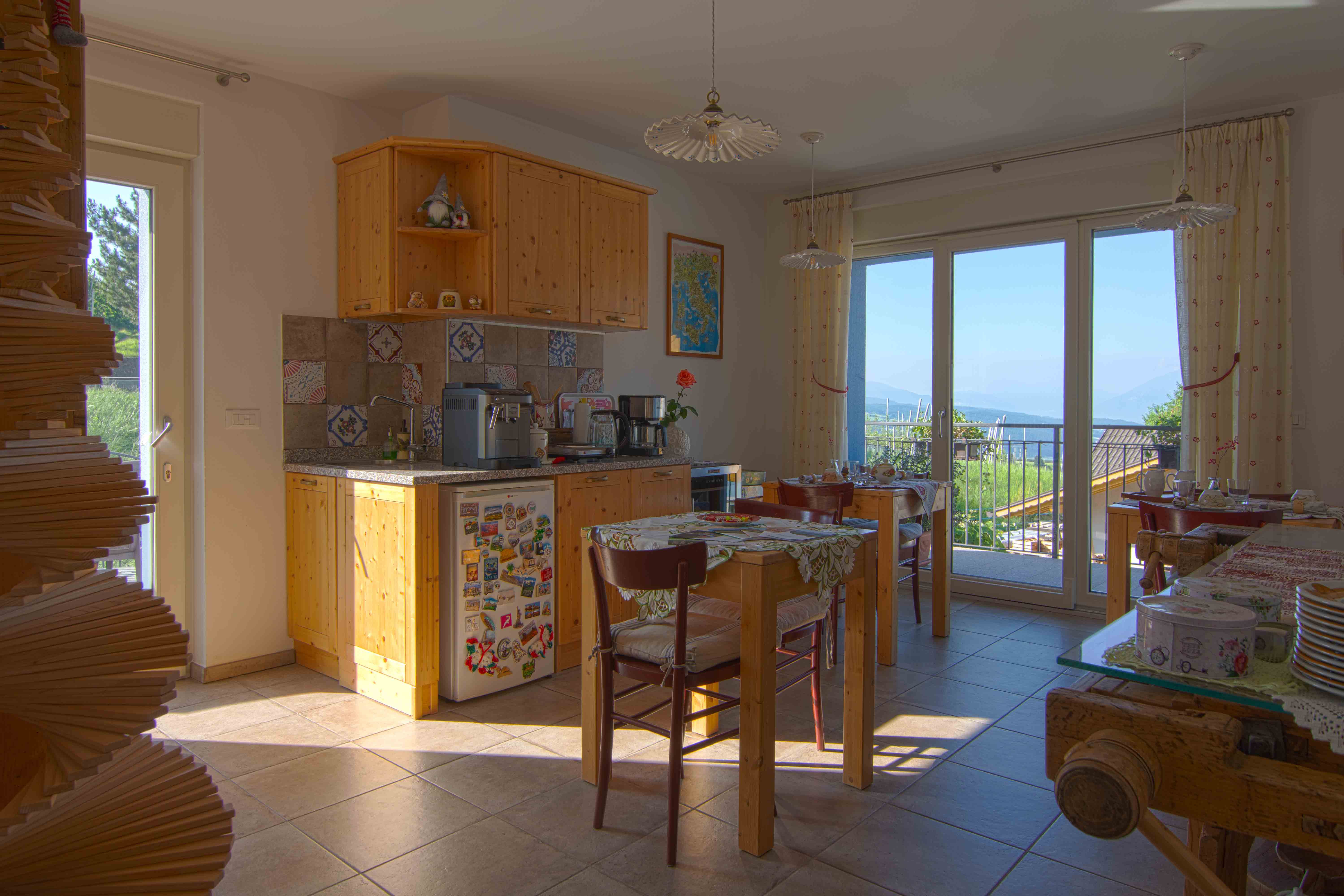 Sala colazione Raina con tavoli apparecchiati, prodotti locali e luce naturale.