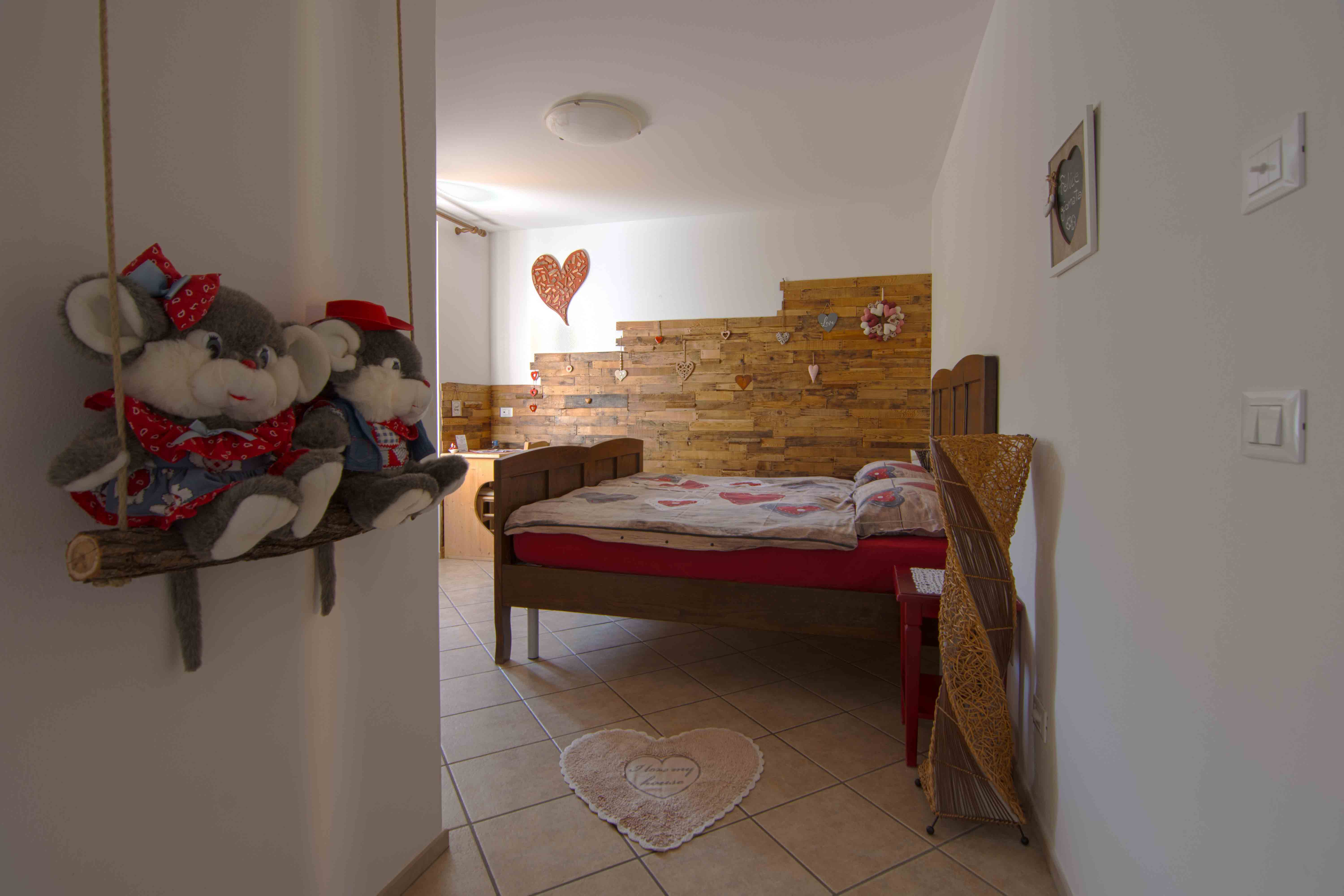 Camera Romantica. Camera spaziosa con decorazioni raffinate in legno con paesaggi di montagna tipici del Trentino.