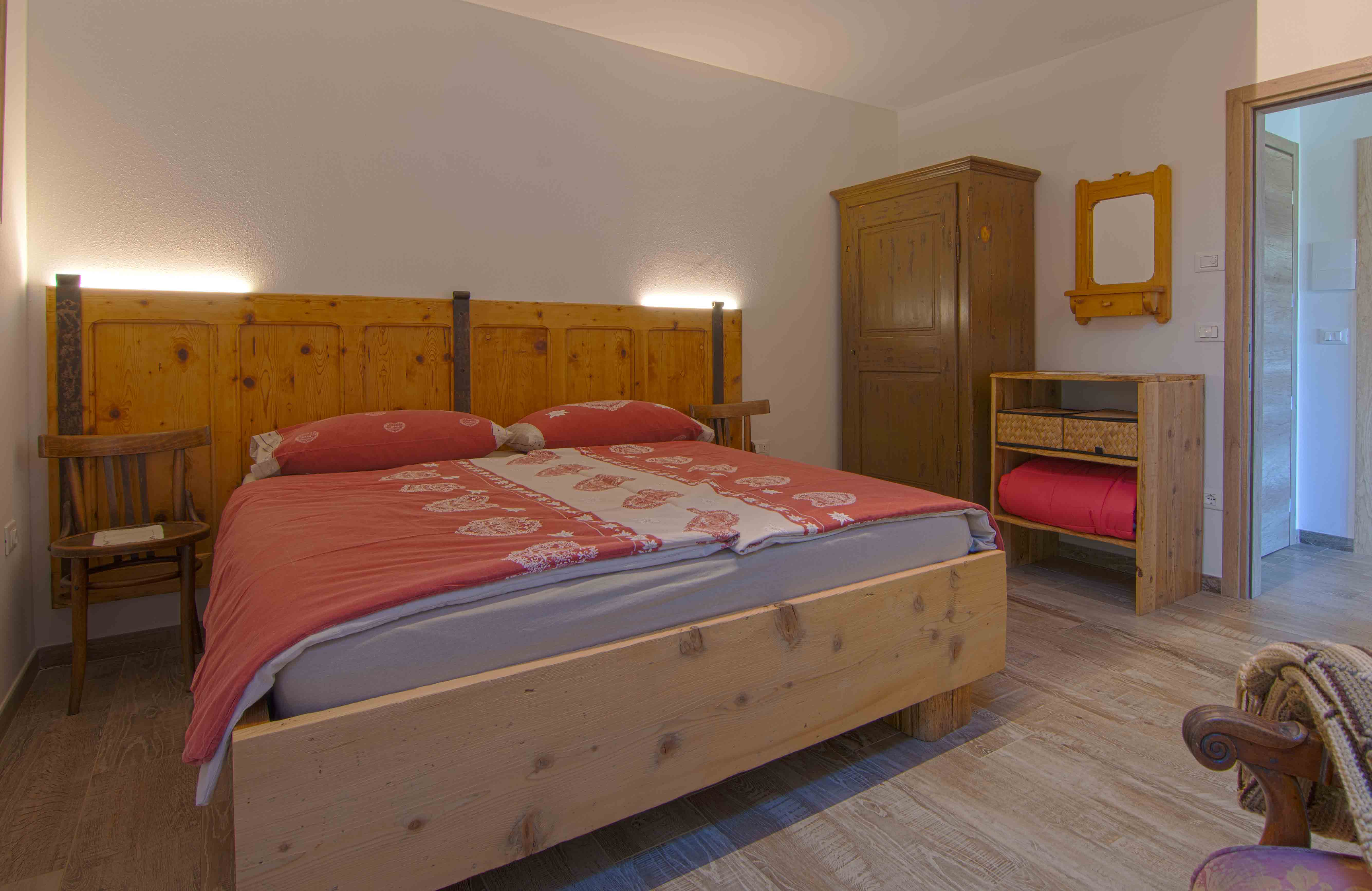 Camera Sorasu. Camera da letto matrimoniale con decorazioni in legno.