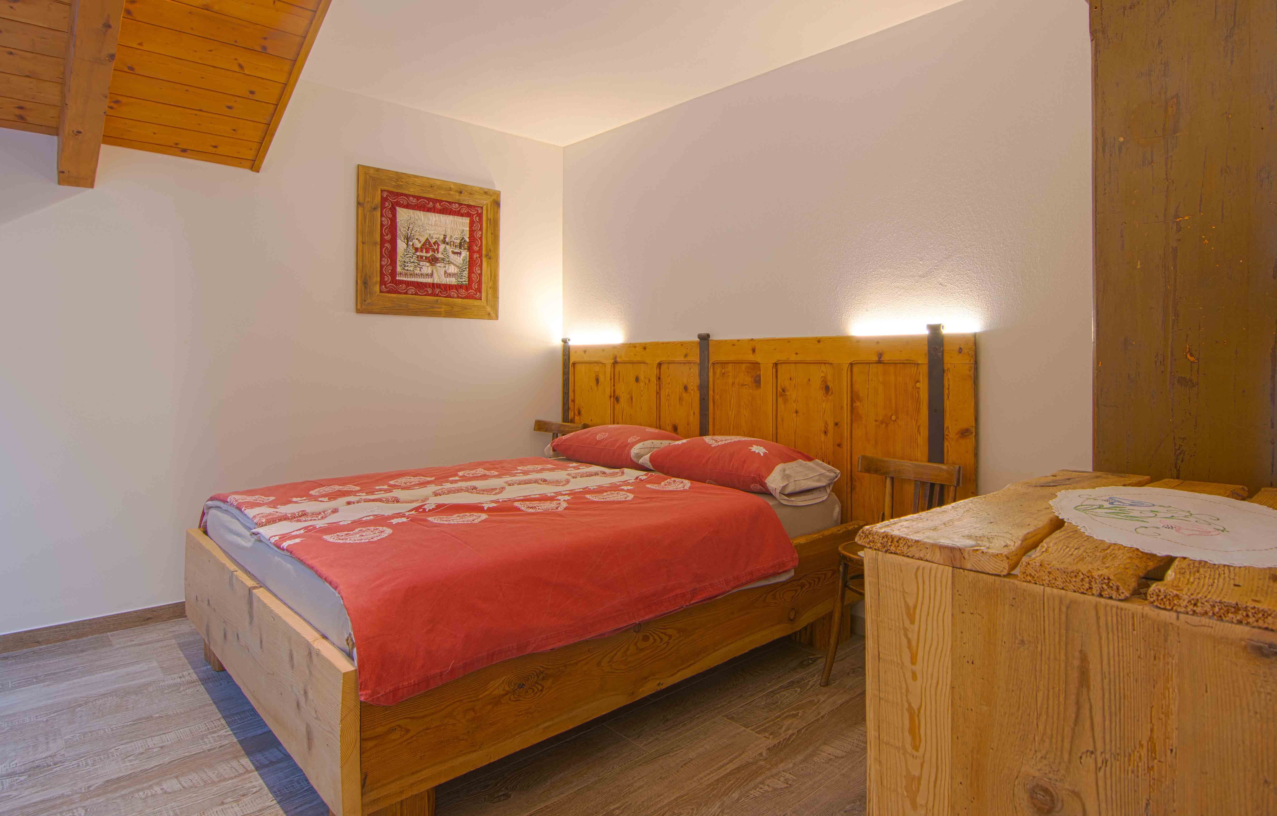 Camera Sorasu. Romantico letto matrimoniale in camera spaziosa ed elegante con decorazioni in legno.